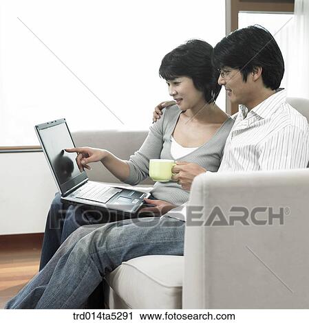 Stock Image - a man on a sofa and a woman working with a notebook. Fotosearch