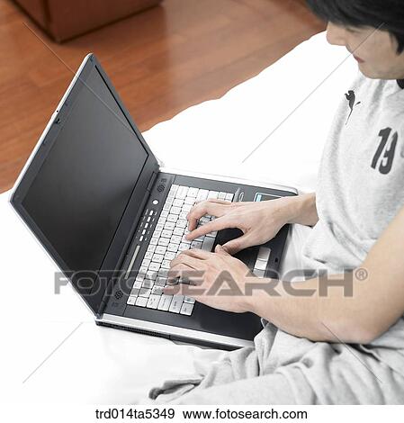 a man talking on a phone and looking at a notebook on a bed View Large Photo Image Stock Photo - a man talking on a phone and looking at a notebook on a bed. Fotosearch