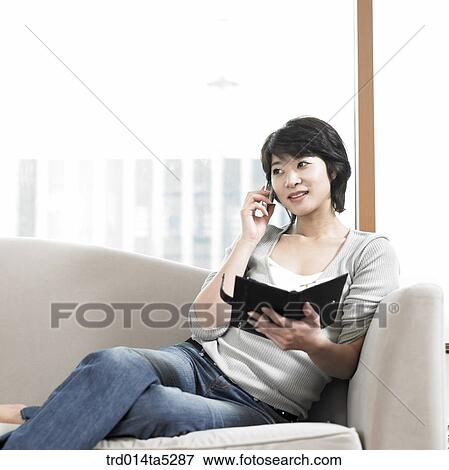 a woman talking on a phone and holding a diary View Large Photo Image Stock Photo - a woman talking on a phone and holding a diary. Fotosearch