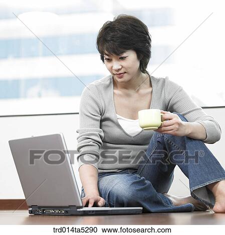 Stock Image - a woman working with a computer on a floor. Fotosearch