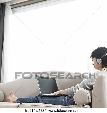 Picture - a woman working with a notebook on a sofa. Fotosearch