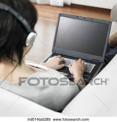 Stock Photography - a woman working with a notebook on a sofa. Fotosearch