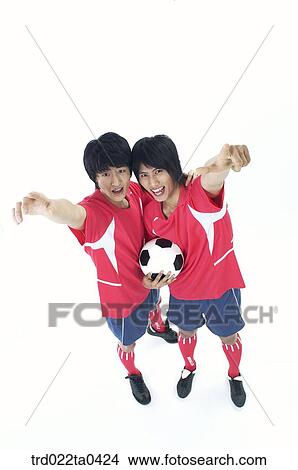Picture - two men holding their hands with a ball high. Fotosearch