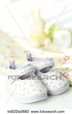 Stock Image - baby supplies/a baby shoe and baby clothes in front of a window. Fotosearch