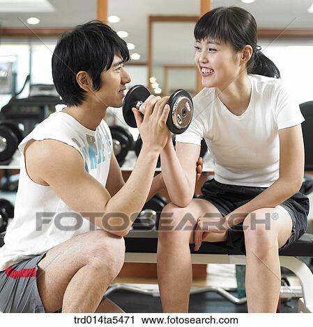Stock Image - a couple exercising with dumbbells at a fitness club. Fotosearch