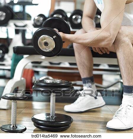a man exercising with dumbbells at a fitness club View Large Photo Image Stock Photo - a man exercising with dumbbells at a fitness club. Fotosearch