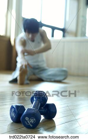 Picture - a stretching man and dumbbells. Fotosearch