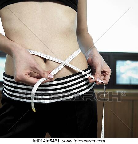 Stock Image - a woman measuring her waist . Fotosearch