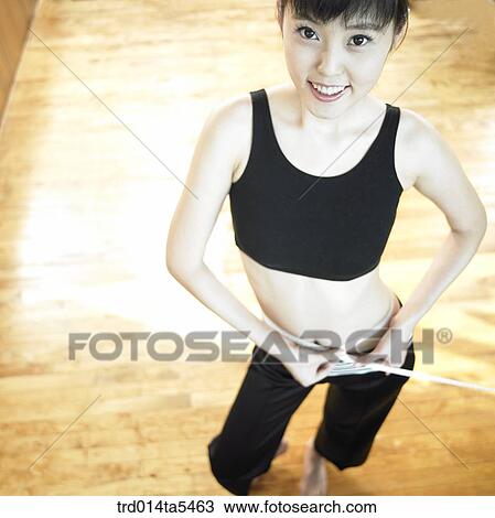 Stock Image - a woman measuring her waist . Fotosearch