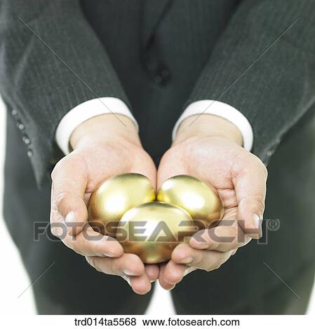 Stock Photo - business concept/a businessman's hands holding a golden egg. Fotosearch