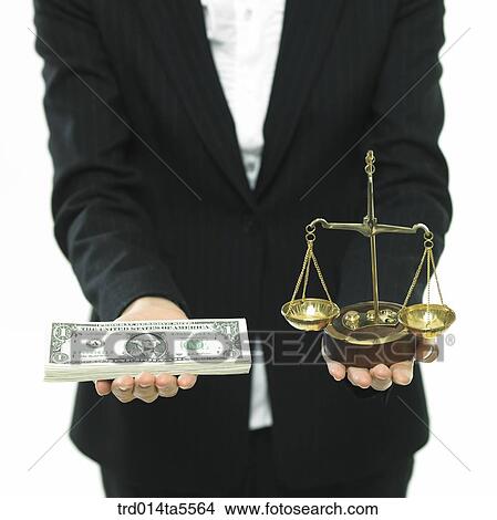 Picture - business concept/businesswoman's hand holding money and a scale. Fotosearch