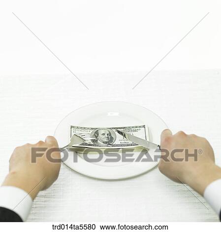 Stock Image - business concept/cutting a paper money by using a knife and a fork . Fotosearch