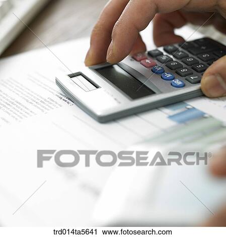 Stock Image - finance/a calculator and a hand on a document. Fotosearch