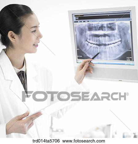 Stock Photograph - medicine/ a dentist looking at X-ray photographs. Fotosearch