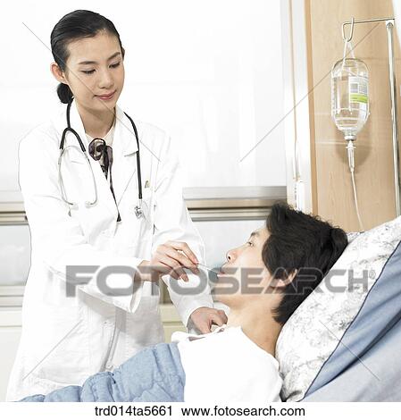 Stock Image - medicine/ a doctor and a patient with a thermometer. Fotosearch