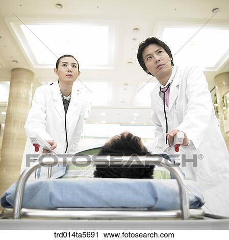 Stock Image - medicine/ a doctor moving an emergent patient. Fotosearch