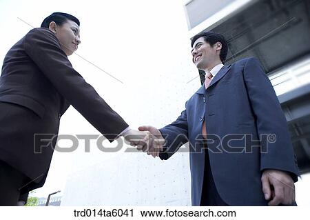 Stock Image - a businessman and a businesswoman shaking their hands. Fotosearch