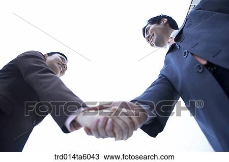 Stock Image - a businessman and a businesswoman shaking their hands. Fotosearch