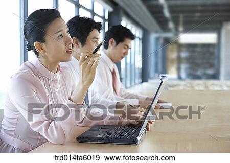 Stock Photo - a explaining businesswoman and a hearing businessman in a conference room. Fotosearch