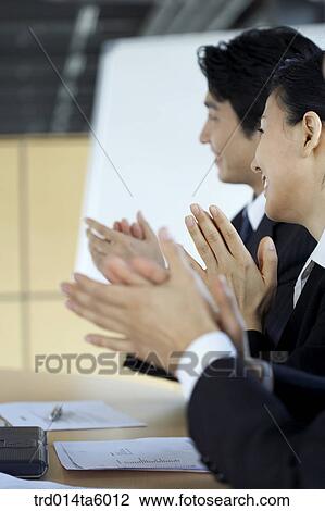 Stock Image - an applausing businessman and a businesswoman. Fotosearch