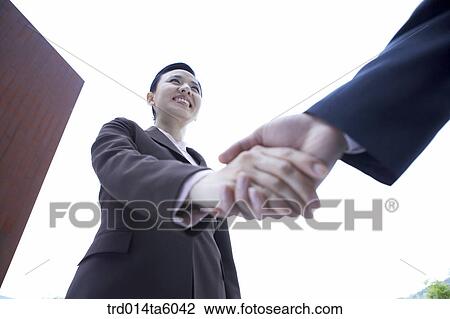 Stock Image - businesswomen shaking their hands. Fotosearch