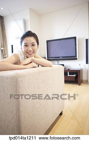 Stock Image - Korean, Asian, person, woman, inside, living room, sofa. Fotosearch