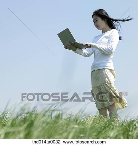 a woman doing something with a notebook on the grass View Large Photo Image Stock Image - a woman doing something with a notebook on the grass. Fotosearch