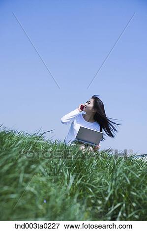 a woman doing something with a notebook and calling with a mobile phone View Large Photo Image Stock Photo - a woman doing something with a notebook and calling with a mobile phone. Fotosearch