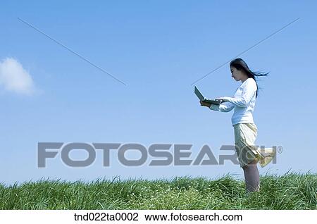 a woman doing something with a PDA on the grass View Large Photo Image Stock Image - a woman doing something with a PDA on the grass. Fotosearch