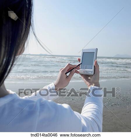 a woman doing something with a PDA on the grass View Large Photo Image Stock Photograph - a woman doing something with a PDA on the grass. Fotosearch