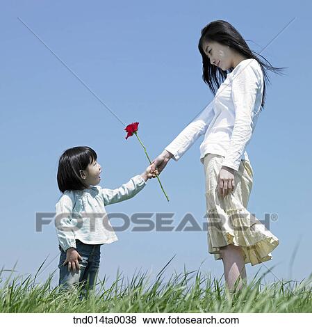 Stock Photo - a woman giving a rose to a child. Fotosearch