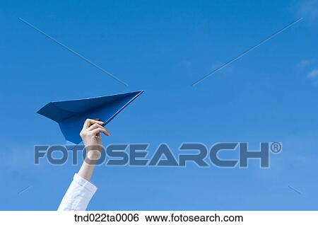 Stock Photograph - a woman playing with a paper airplane. Fotosearch