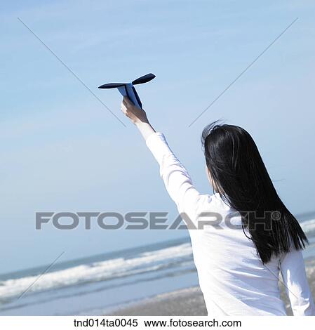 a woman playing with a paper airplane in a seaside View Large Photo Image Stock Photography - a woman playing with a paper airplane in a seaside. Fotosearch