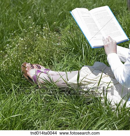 Picture - a woman reading a book on the grass. Fotosearch