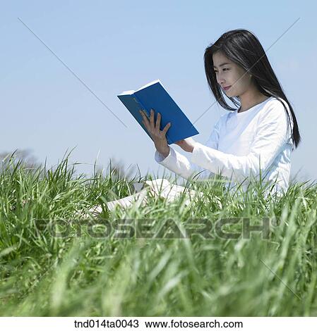 a woman reading a book on the grass View Large Photo Image Stock Image - a woman reading a book on the grass. Fotosearch