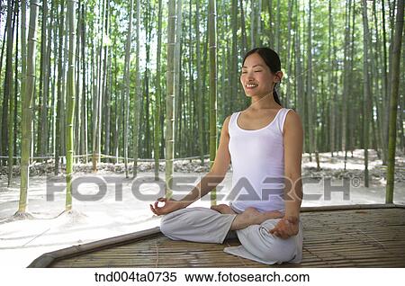 Stock Photography - a woman doing Yoga at a pavilion in a bamboo tree forest. Fotosearch