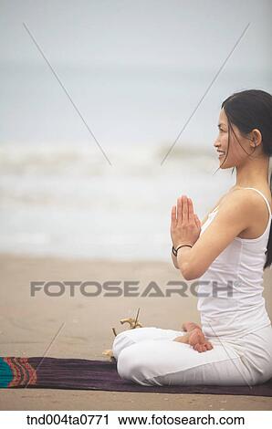 Stock Image - a woman doing Yoga in a seashore. Fotosearch