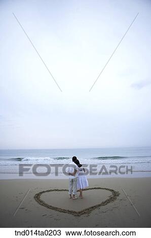 couple are in the circle of hear on the sand beach View Large Photo Image Stock Image - couple are in the circle of hear on the sand beach. Fotosearch