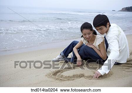 couple drawing hear on the sand View Large Photo Image Picture - couple drawing hear on the sand. Fotosearch