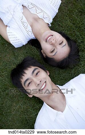 Stock Photo - couple laying on the grass feild. Fotosearch