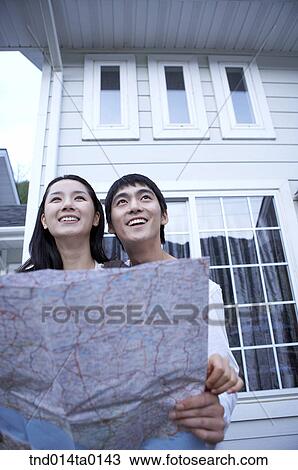 Stock Image - happy married couple with map in ther honeymoon. Fotosearch