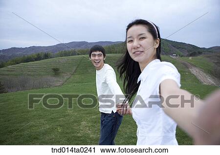 Stock Image - holding hands happy, merry couple. Fotosearch