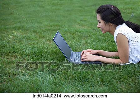 Picture - woman with computer on the grass field. Fotosearch