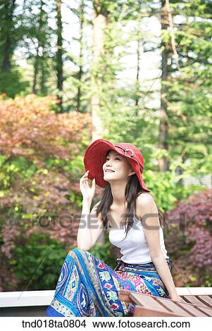 Picture - woman sitting on the bench of the park. Fotosearch