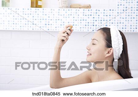woman spraying oil on her face in the bath tub View Large Photo Image Stock Photography - woman spraying oil on her face in the bath tub. Fotosearch
