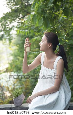 Stock Image - woman spraying water on her face. Fotosearch