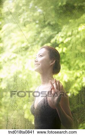 Stock Image - woman standing outside the glass pane. Fotosearch