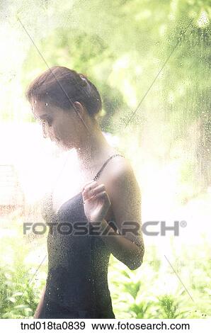 Stock Photo - woman standing outside the glass pane. Fotosearch