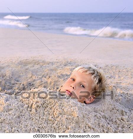 Gros Plan De A Garçon Regarder Effrayé à Les Téléspectateur Quoique Enterré Dans Sable Plage Banque De Photographies