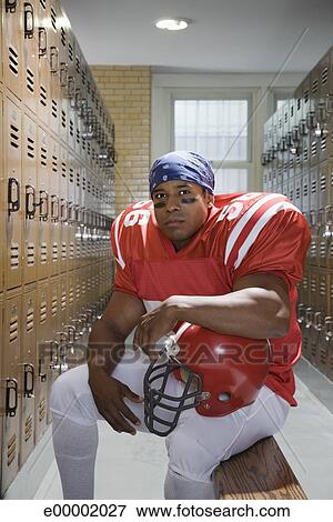 Football Player Sitting On Bench In Locker Room Stock Photo